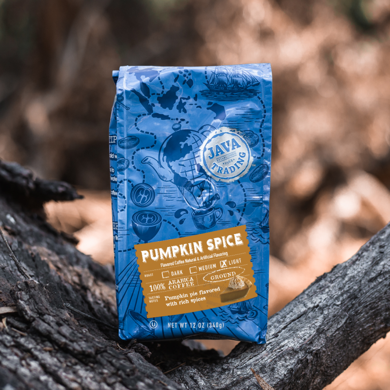 Java Trading blue bag of Pumpkin Spice flavored coffee perched on a tree limb during fall
