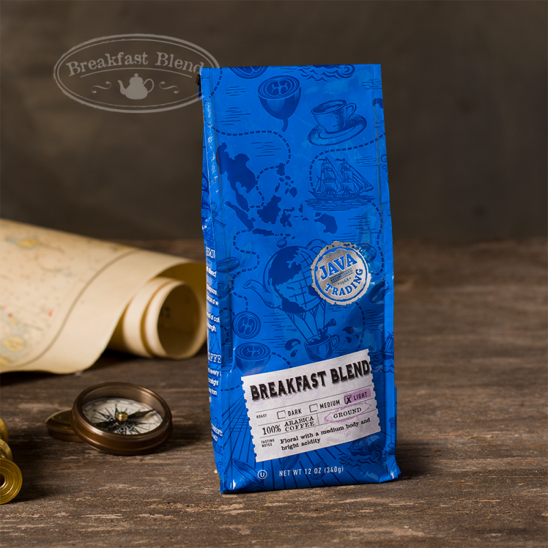 Bag of 12 ounce of Breakfast Blend coffee on a wooden table with rolled map and compass